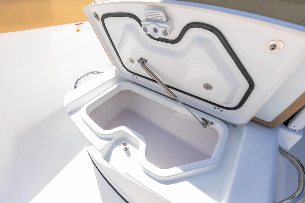 Open cooler with black handles and drain valve in boat console storage area
