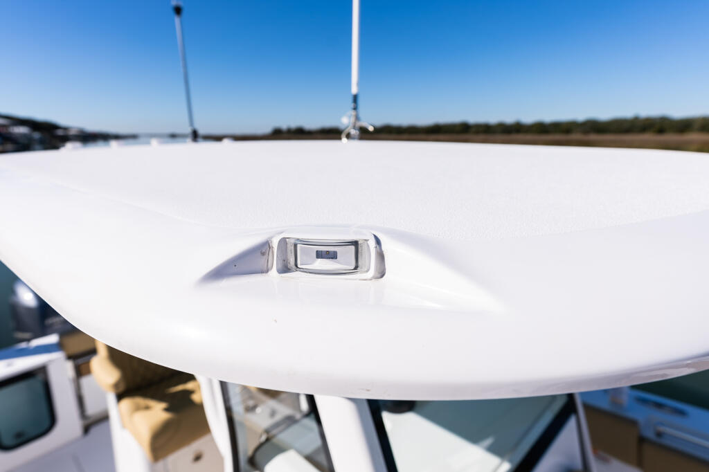 Molded-in navigation light detail on white hard-top with marina and antenna visible in background