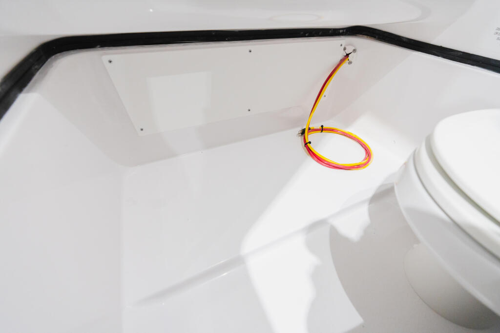 Orange and yellow fishing rod mounted in white boat hull with black trim and stainless steel rod holder
