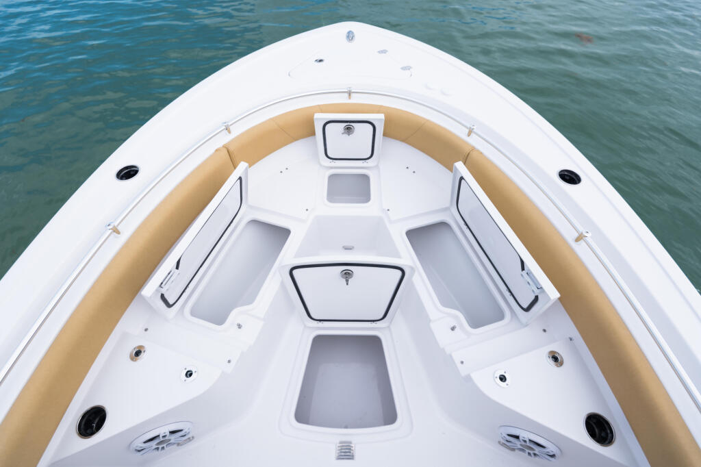 Center console boat bow with tan seating, white gel coat, and multiple storage compartments viewed from above