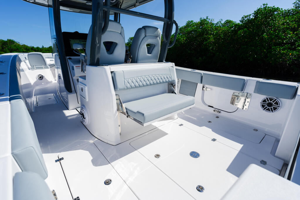 Open cockpit layout with gray upholstered seating, storage compartments, and integrated electronics on a white center console boat
