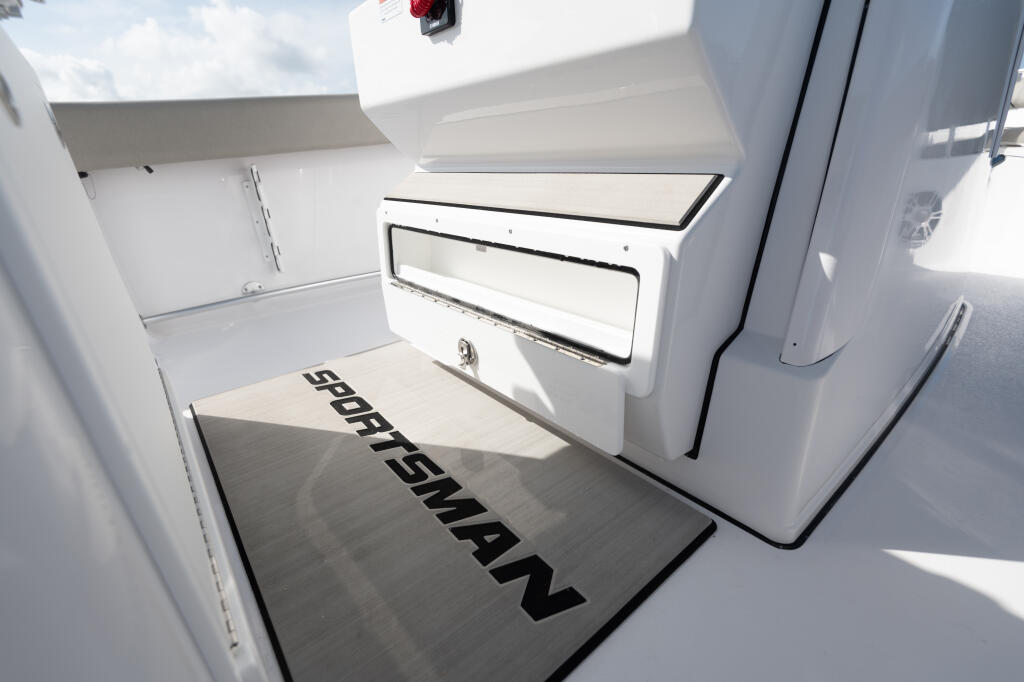 Open storage compartment with cooler access and cabin entry on center console boat