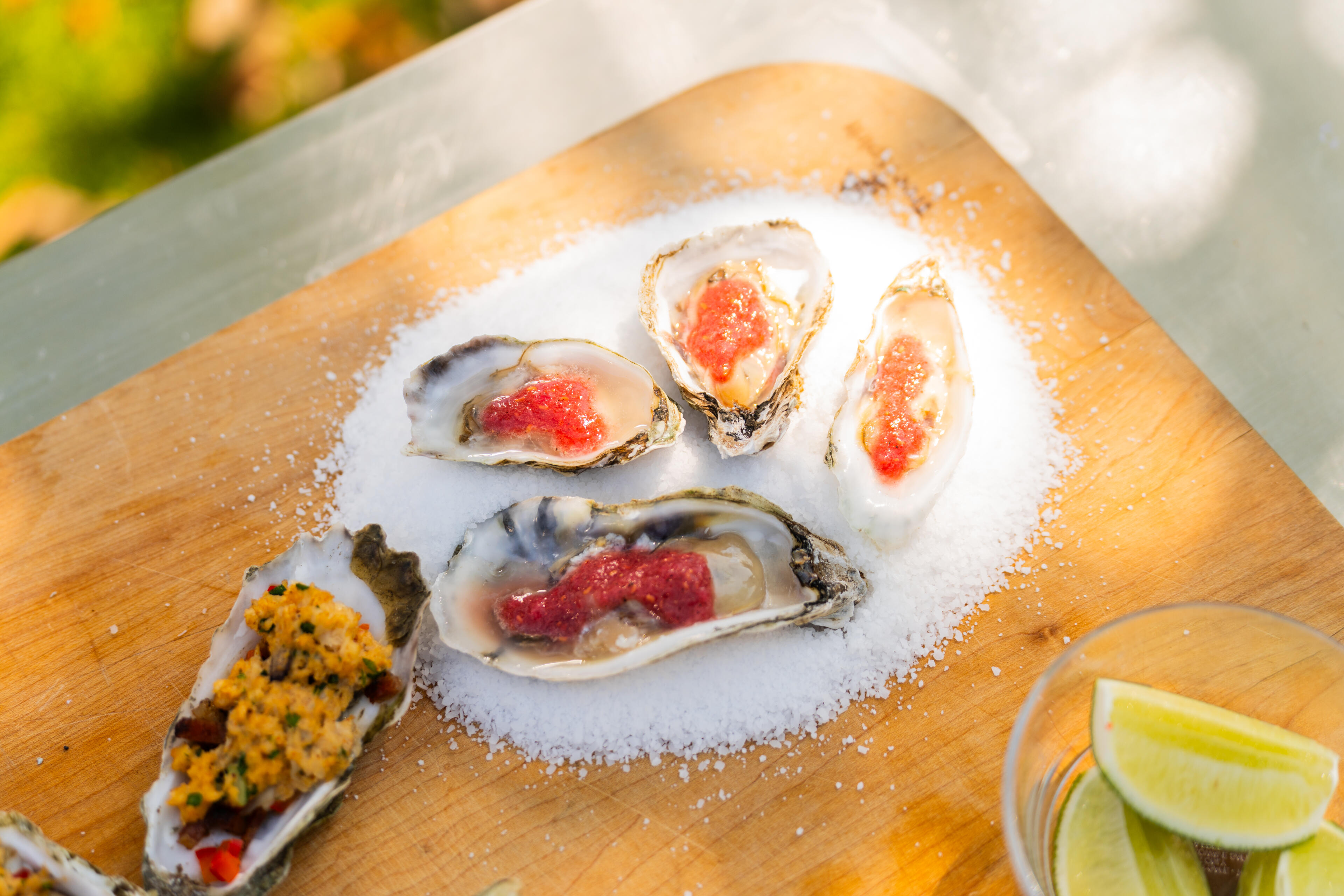 Fresh oysters topped with caviar and served on crushed ice with lime wedge on wooden board