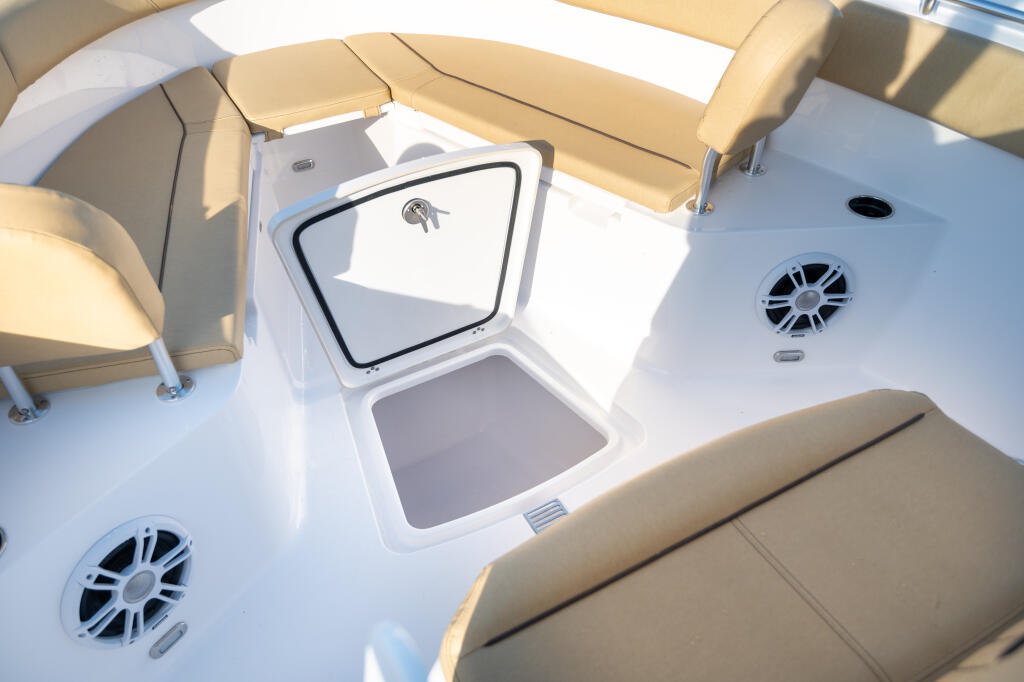 Overhead view of open center console storage box with tan seating and ventilation fans