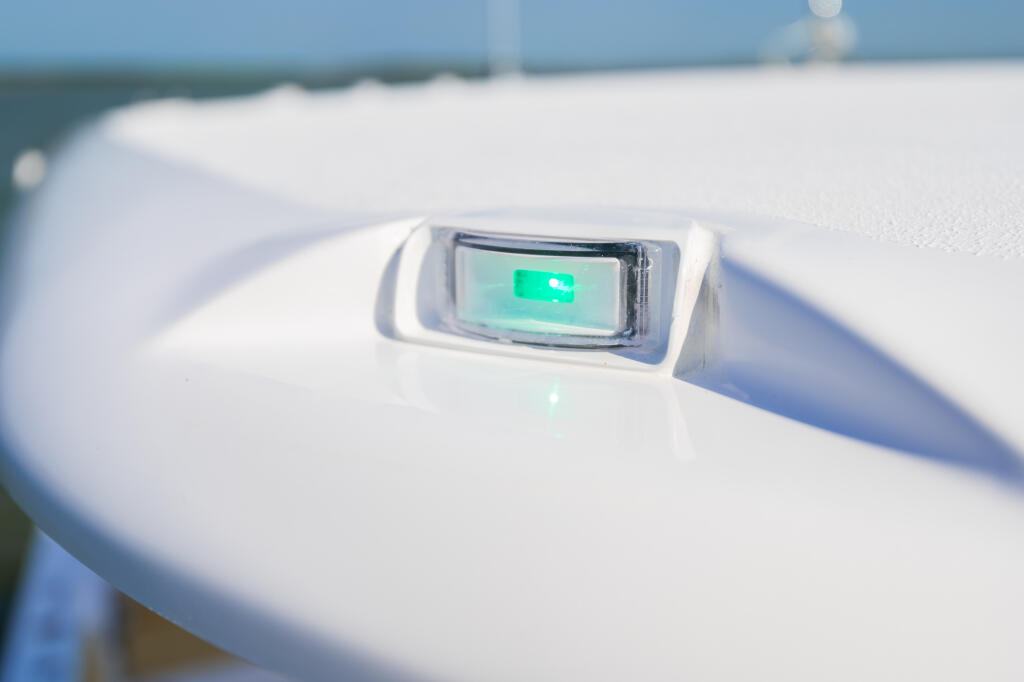 Green navigation light mounted in white hard-top with water and horizon in background