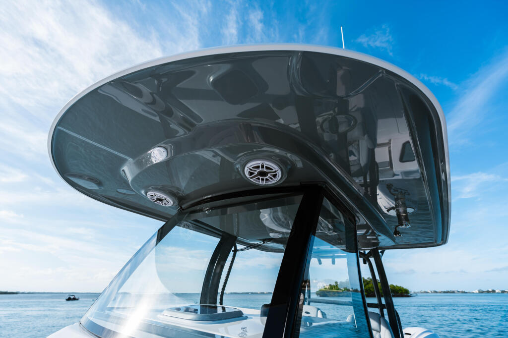 Overhead view of boat helm with tinted hardtop and helm seating visible through windshield on calm blue water