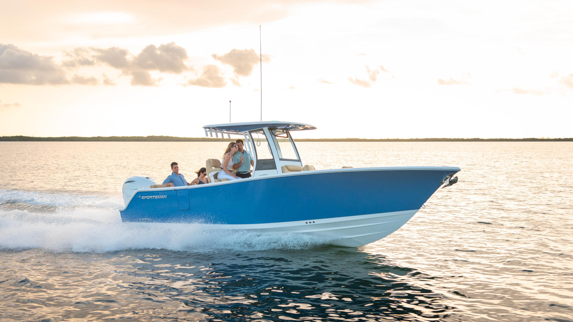 Blue and white center console boat with family aboard cruising through shallow coastal waters near beach at sunset