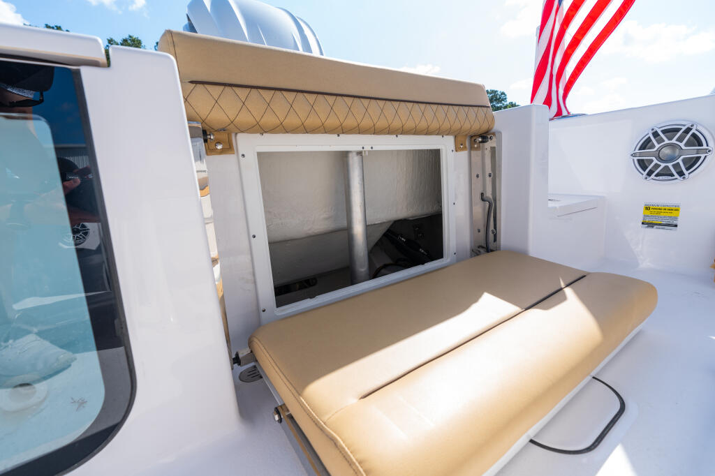Boat cabin rear access hatch with tan awning, cushioned seating, and storage compartment doors