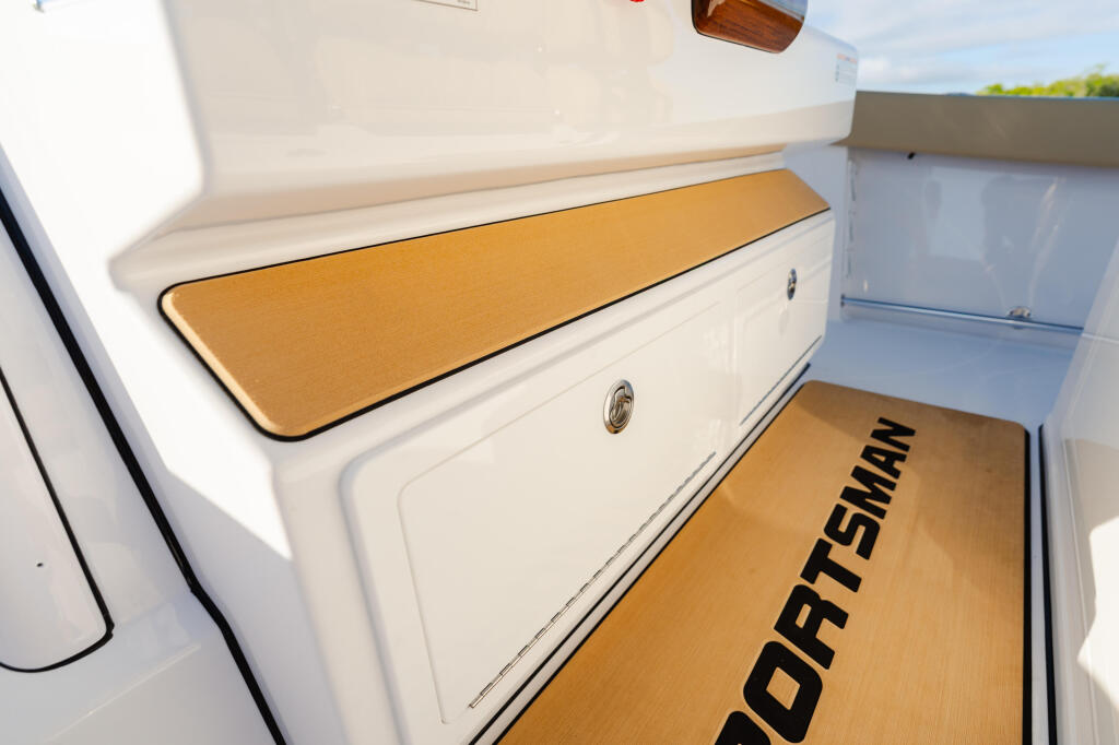 Cabin seating with tan cushions and storage compartments in a white boat interior