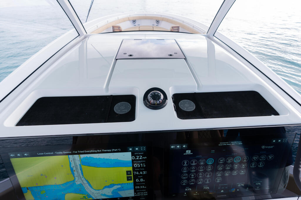 Helm station with dual screens displaying navigation charts and system readouts, compass, and black seating areas