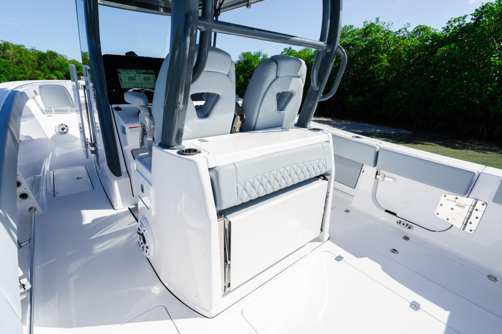 Open center console boat with gray captain's seats, white cushioned gunwale seating, and helm controls visible in bright sunlight