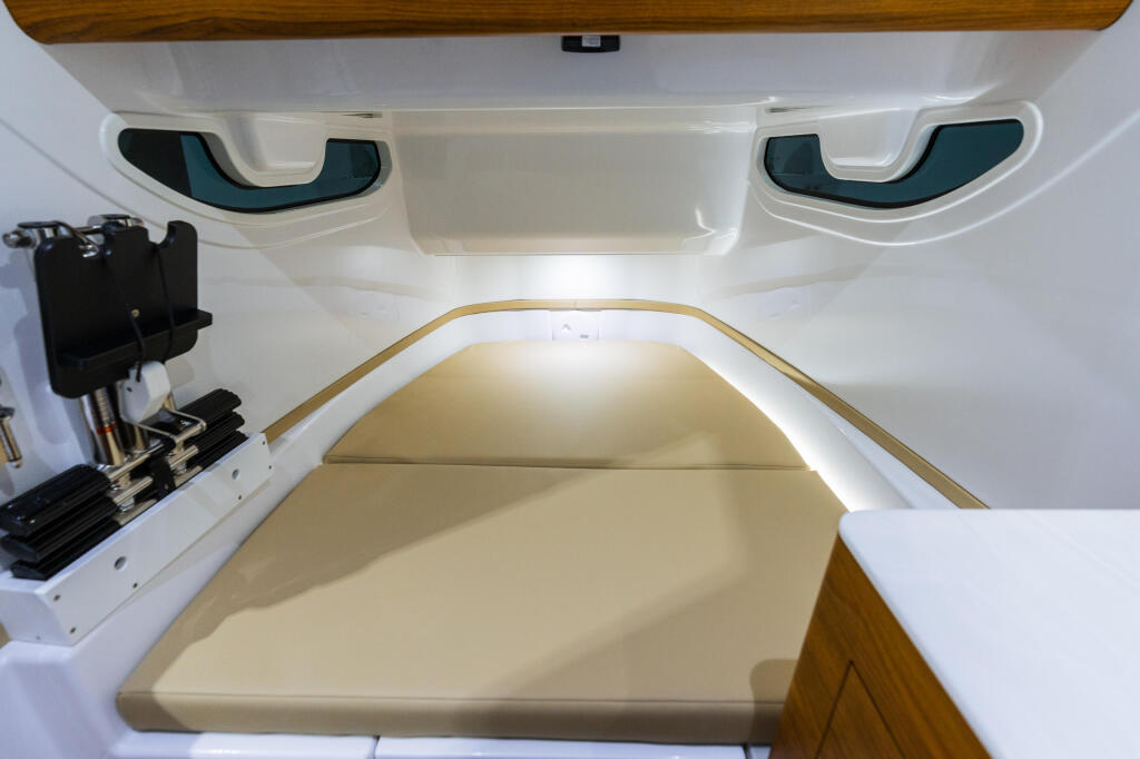 Cabin interior with cream-colored bunk bed, wood trim, overhead windows, and storage compartments