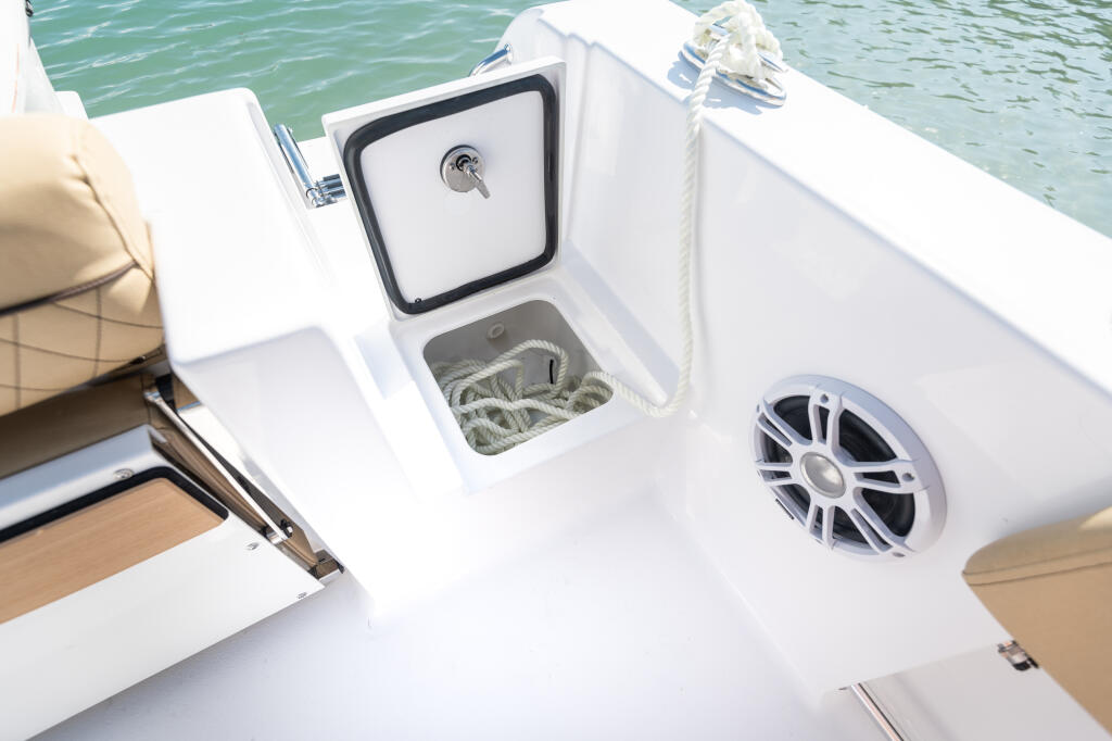 Stern deck with open anchor storage locker and marine speaker detail on center console boat