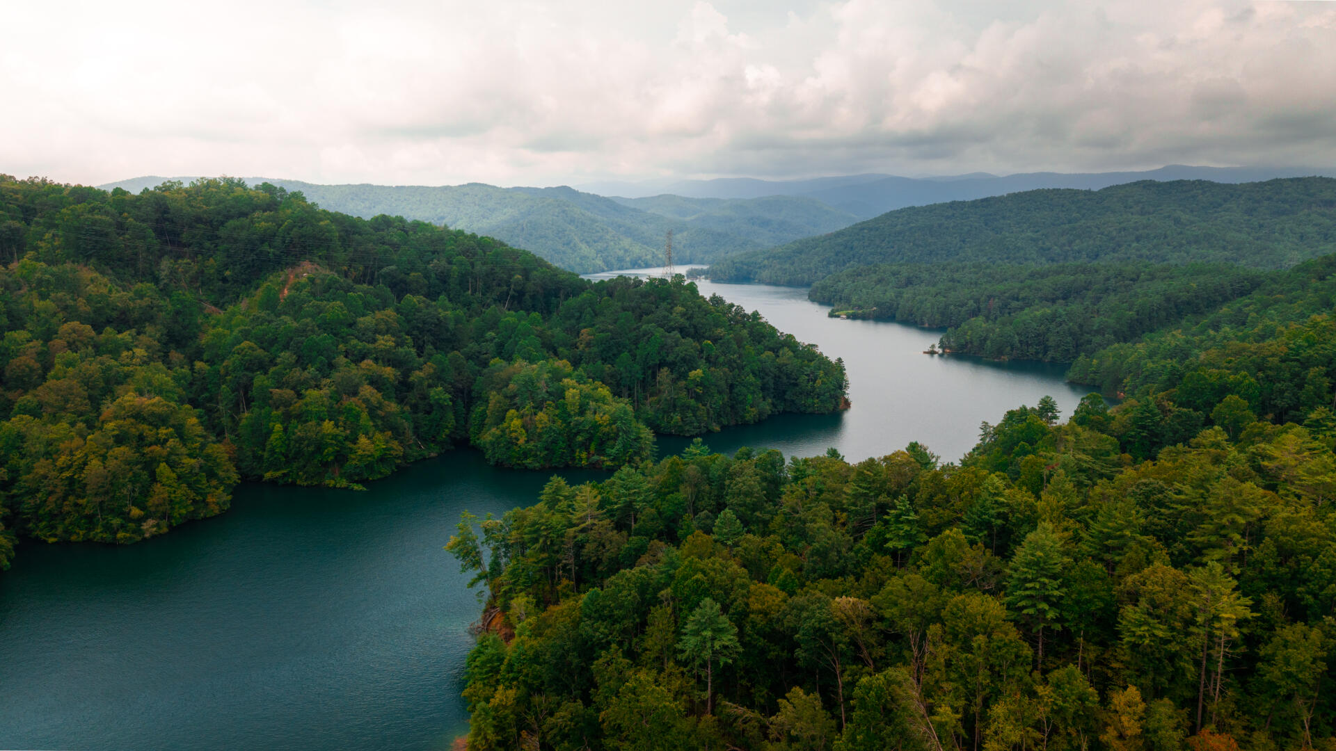 Aerial view of a mountain lake surrounded by dense forested hills with winding waterways