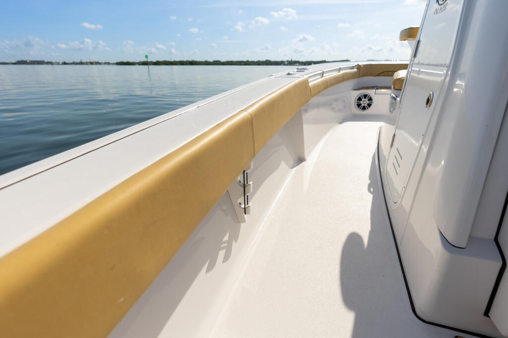 Starboard side deck and tan bolstered seating on a white center console bay boat in calm water