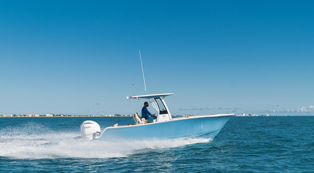 Blue center console boat running through shallow offshore waters near a coastal town
