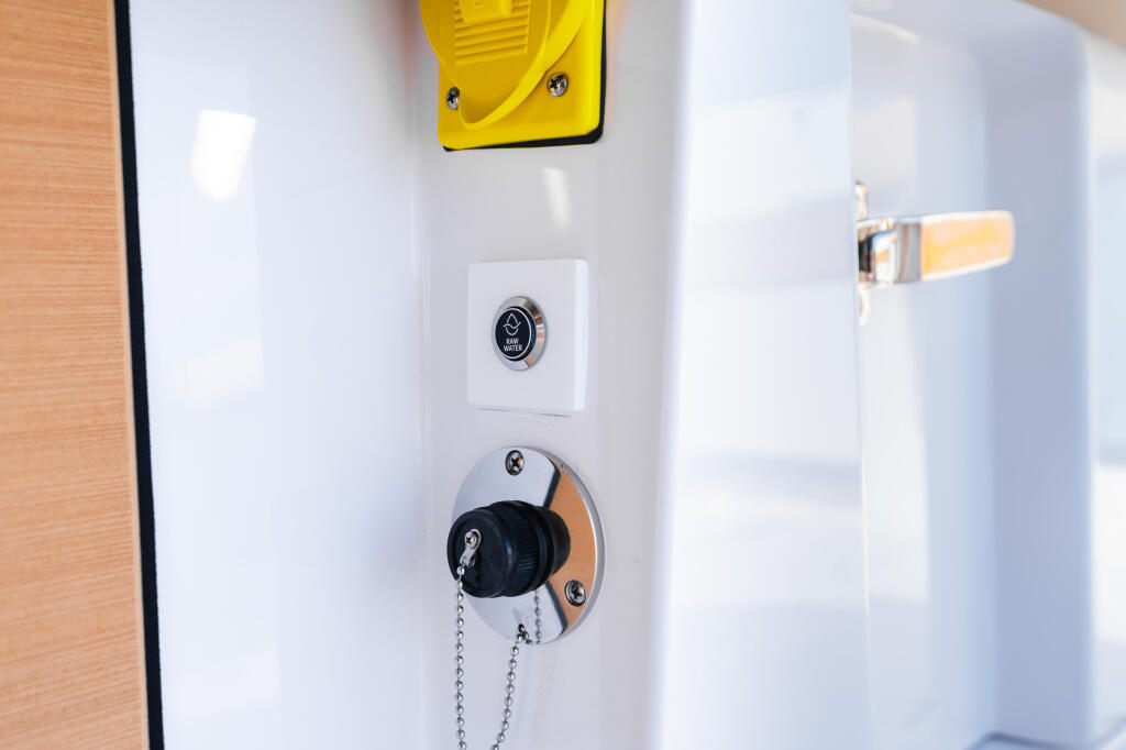 Boat cabin control panel with yellow horn, ignition switch, and engine start button mounted on white wall