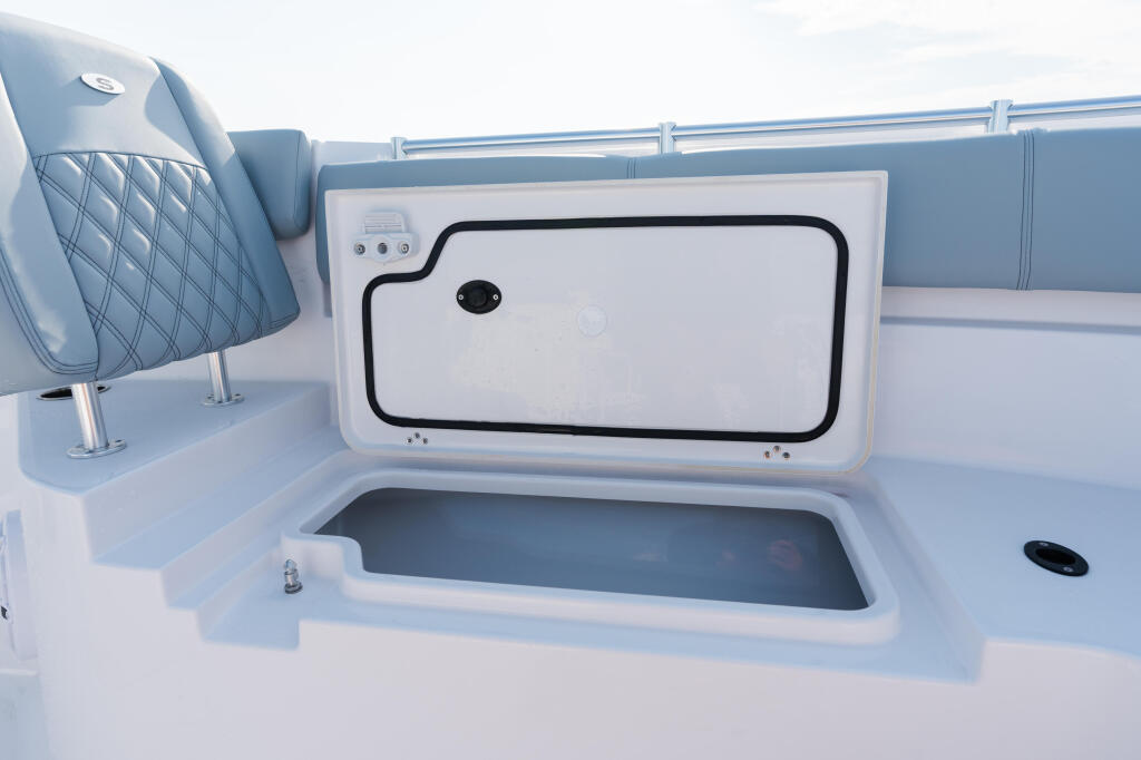 Open livewell with access hatch on a boat's starboard side near quilted gray seating