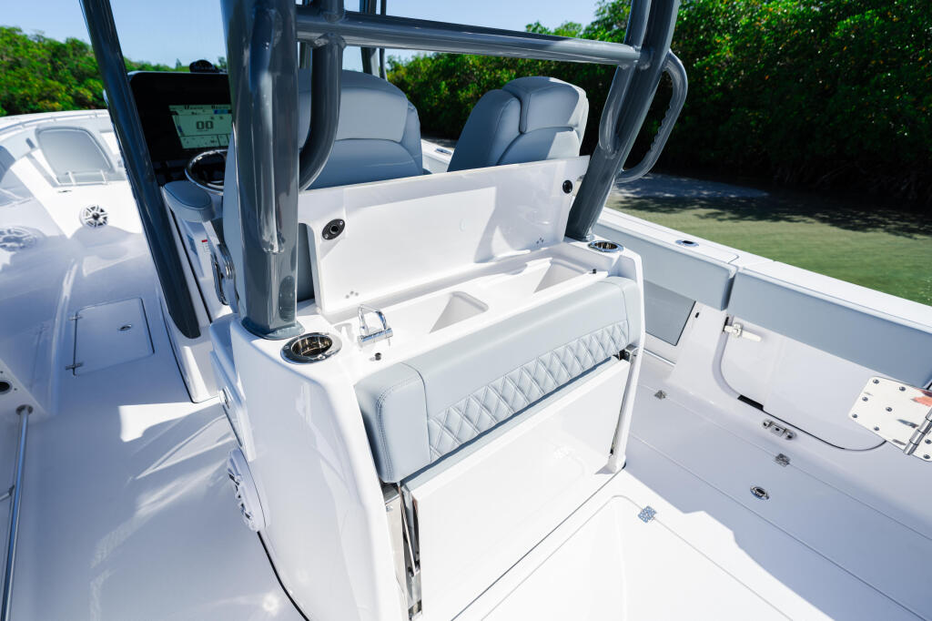 Open boat cockpit with blue upholstered seating, white interior, and hard-top frame in sunny conditions