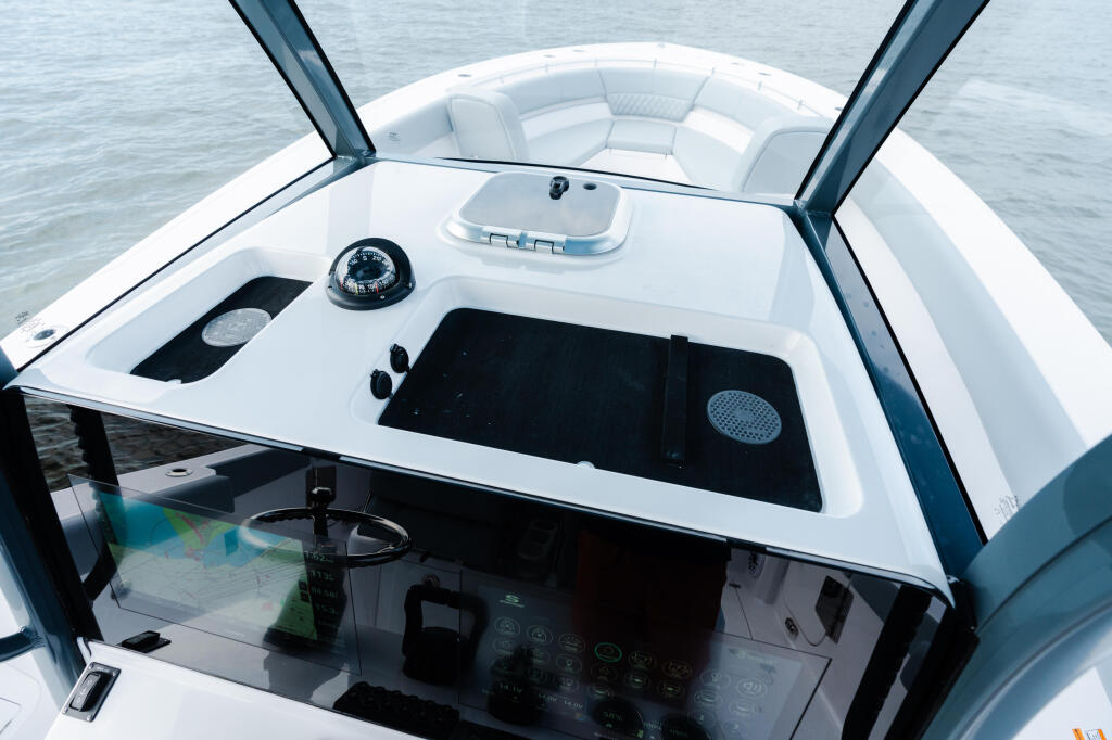 Helm station view of a center console boat with compass, windshield, and black electronics display