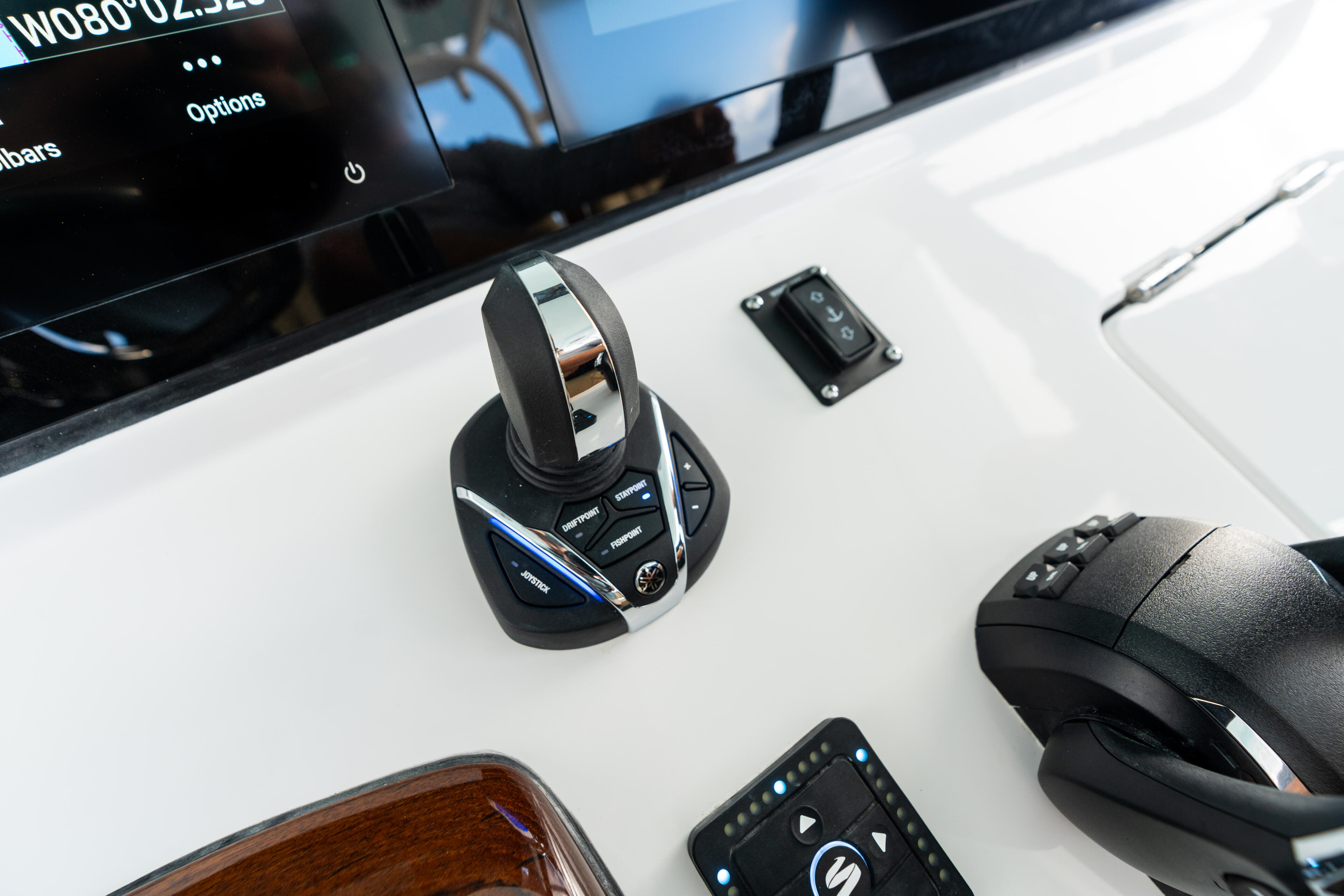 Helm control system with joystick and button panel on boat dashboard near display screen