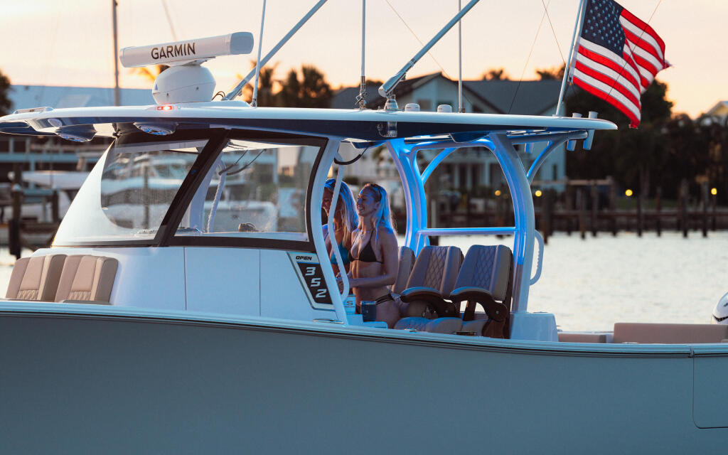 Blue and white center console boat docked at marina at sunset with American flag and Garmin radar