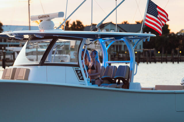 Blue and white center console boat docked at marina at sunset with American flag and Garmin radar