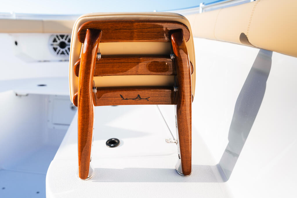 Wooden fishing reel mounted on white boat deck with hardware and rigging visible