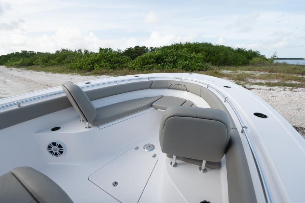 Open bow seating and console area with gray upholstery overlooking sandy beach and mangroves