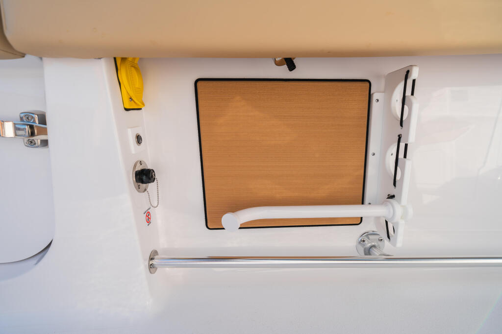Overhead view of boat cabin with wooden window shade, white storage lockers, and helm controls