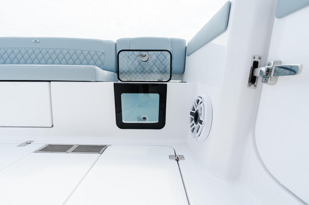 Overhead view of boat's starboard side showing cushioned seating, cabin window, and white hull details