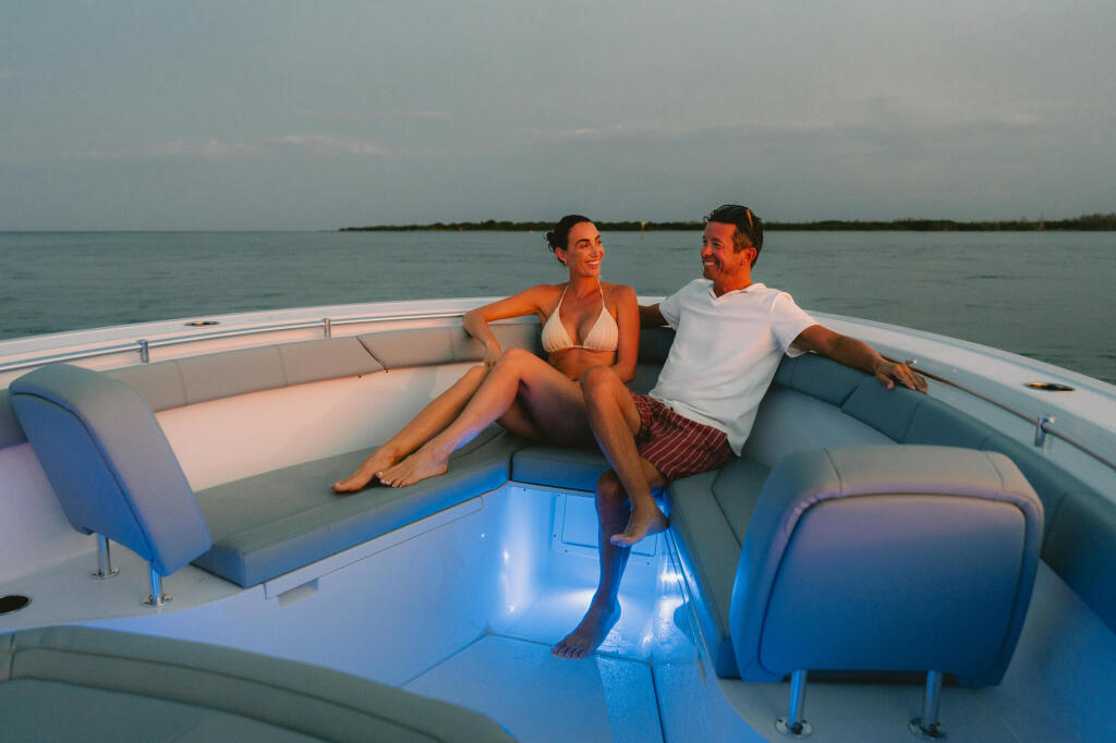 Couple relaxing on cushioned seating in an open boat with calm water and mangroves in the background