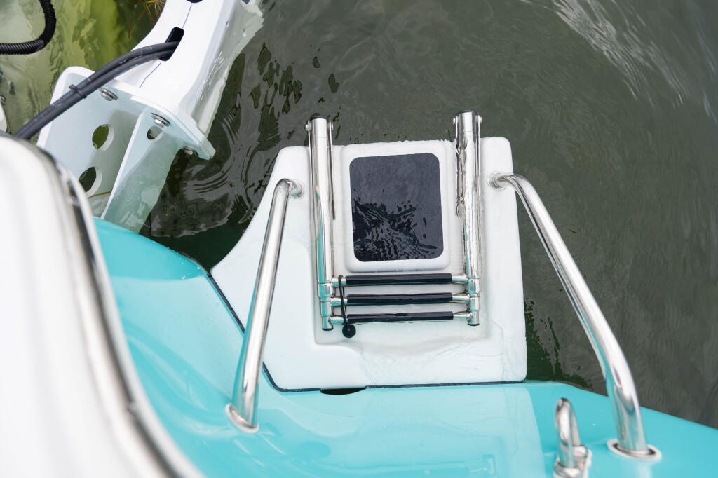 Overhead view of a boat's turquoise and white swim platform with chrome three-step ladder and equipment hatch