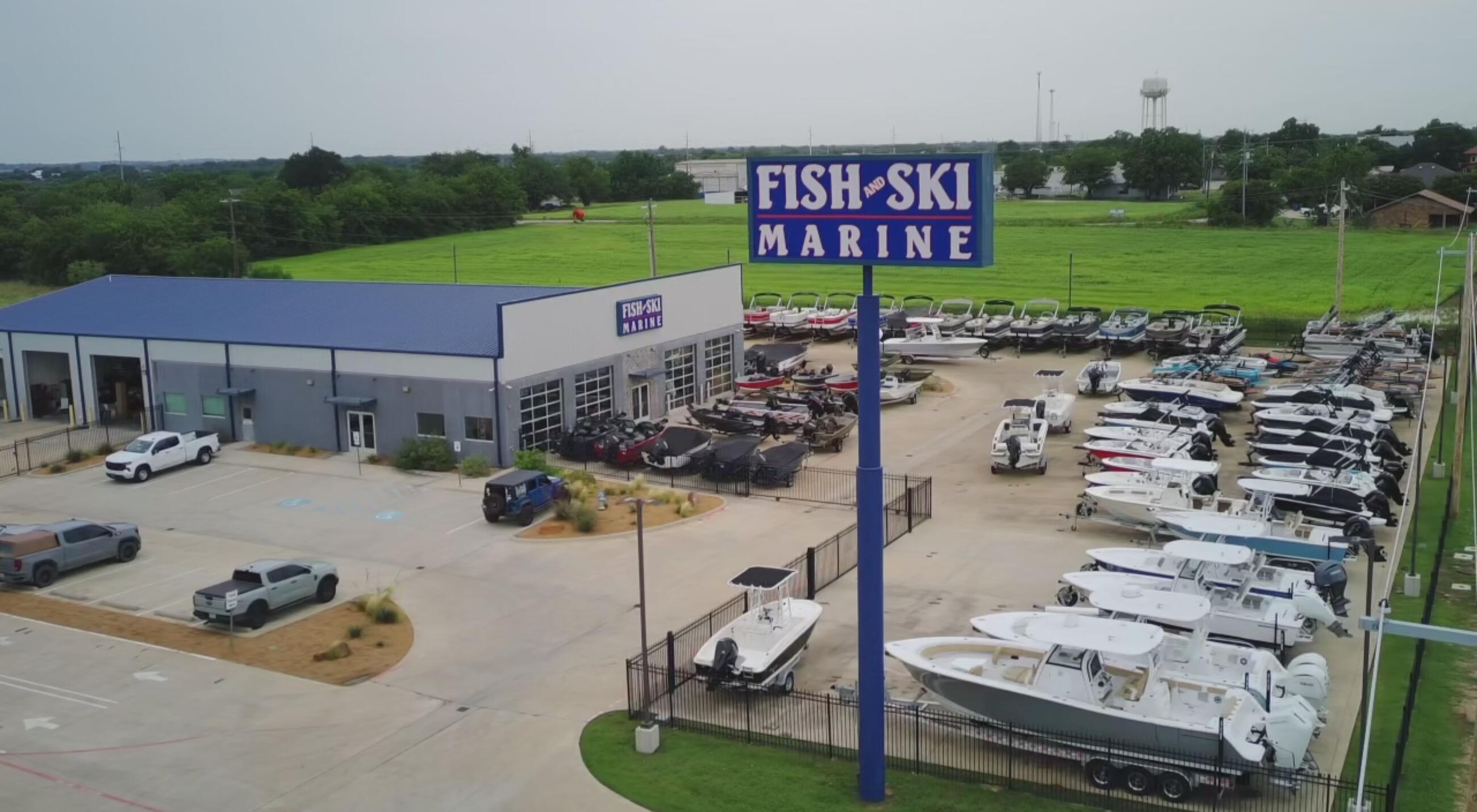 Aerial view of Fish & Ski Marine dealership with boats docked in marina and showroom building in Sanger, Texas