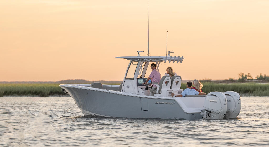 Family of four relaxing aboard a center console boat at sunset with marsh shoreline in background