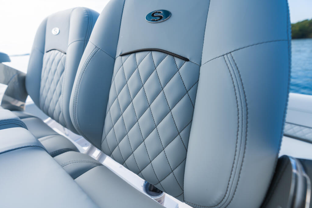 Row of quilted light blue marine-grade seating with branded headrest logos on a boat deck