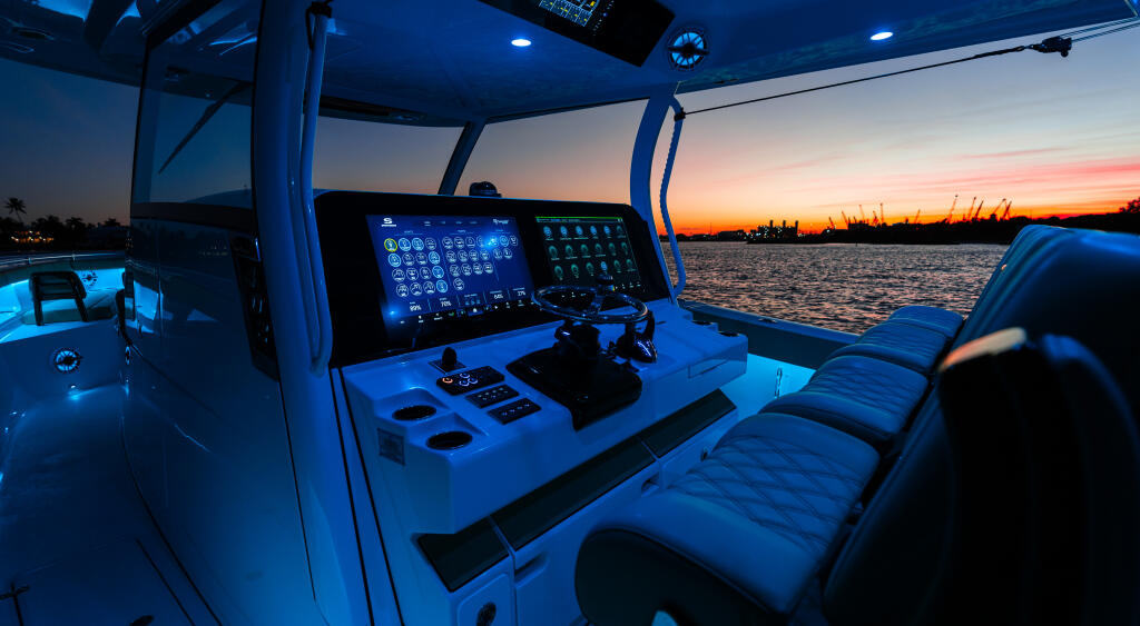Helm station of center console boat at sunset with illuminated electronics and twin screens overlooking calm water