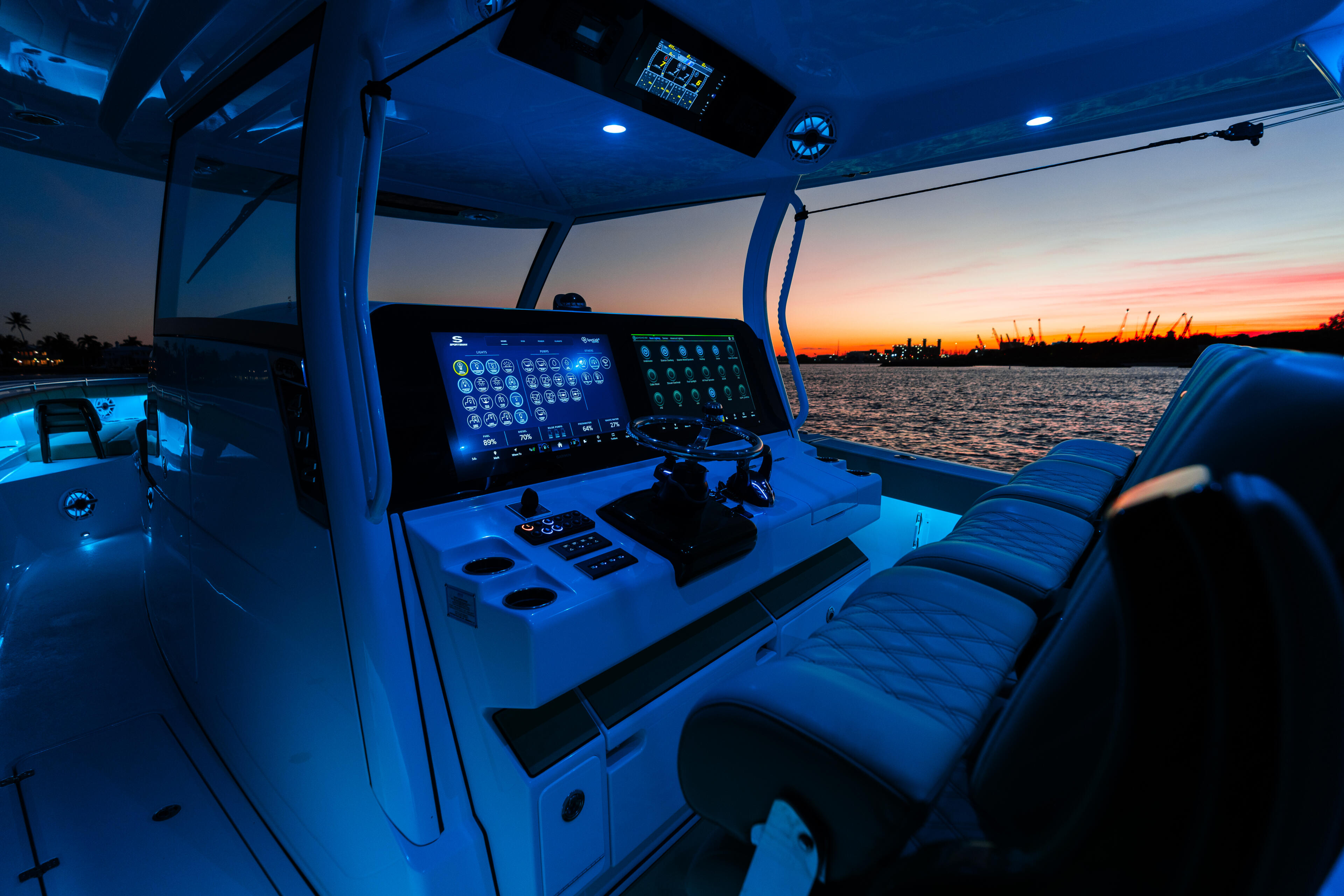 Helm station of center console boat at sunset with illuminated electronics and twin screens overlooking calm water