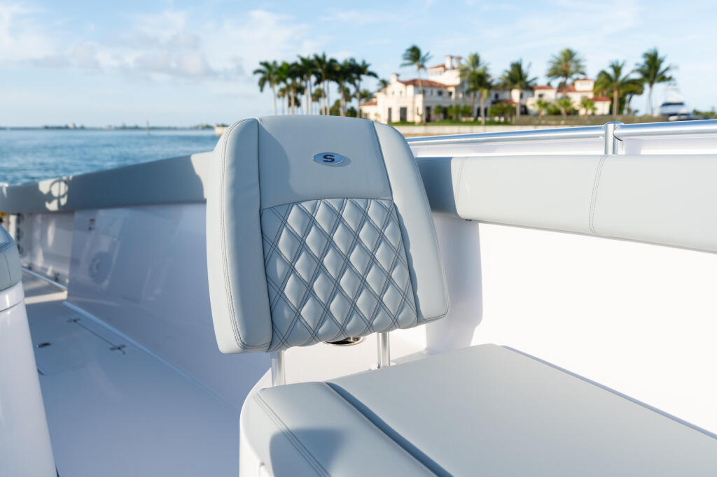Upholstered helm seat with quilted backrest on open boat overlooking waterfront homes