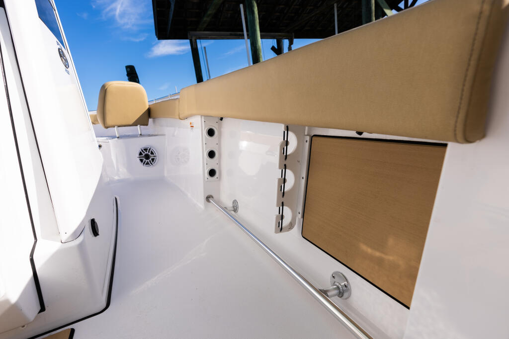 Clean white center console cabin with tan cushioned seating and storage compartments under blue sky