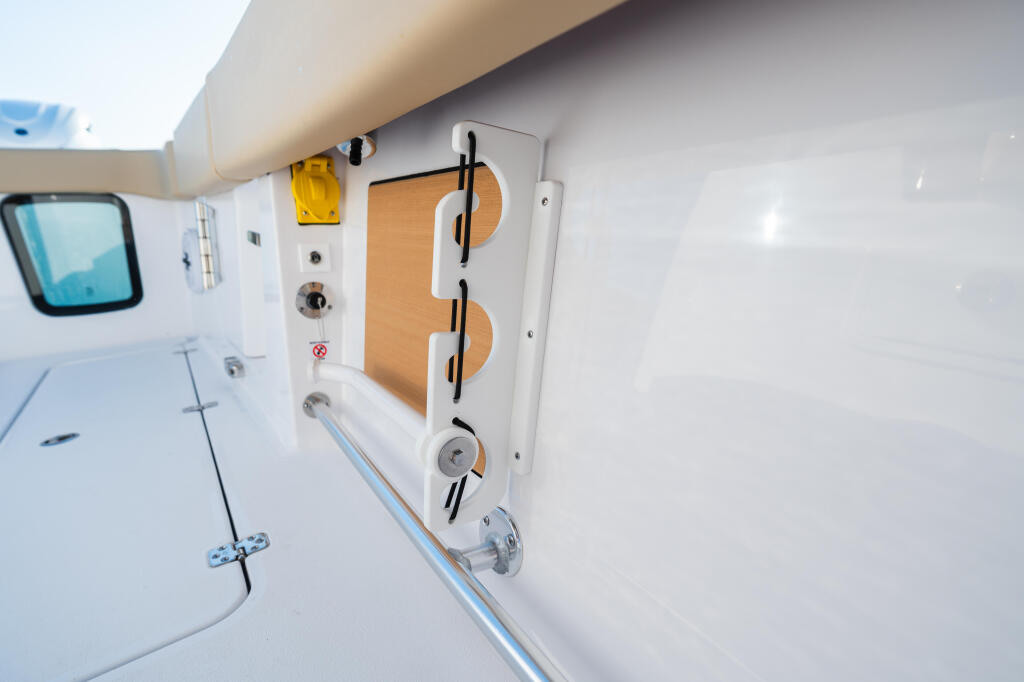 Starboard cabin wall with wooden door, storage compartments, and stainless steel hardware