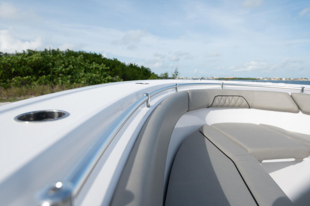 Curved gunwale and recessed bow seating with hand rails on a white center console boat near mangroves