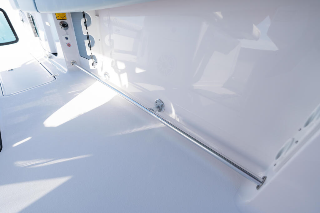 Bright white boat cockpit with open deck space, storage hatch, and chrome rail details in sunlight