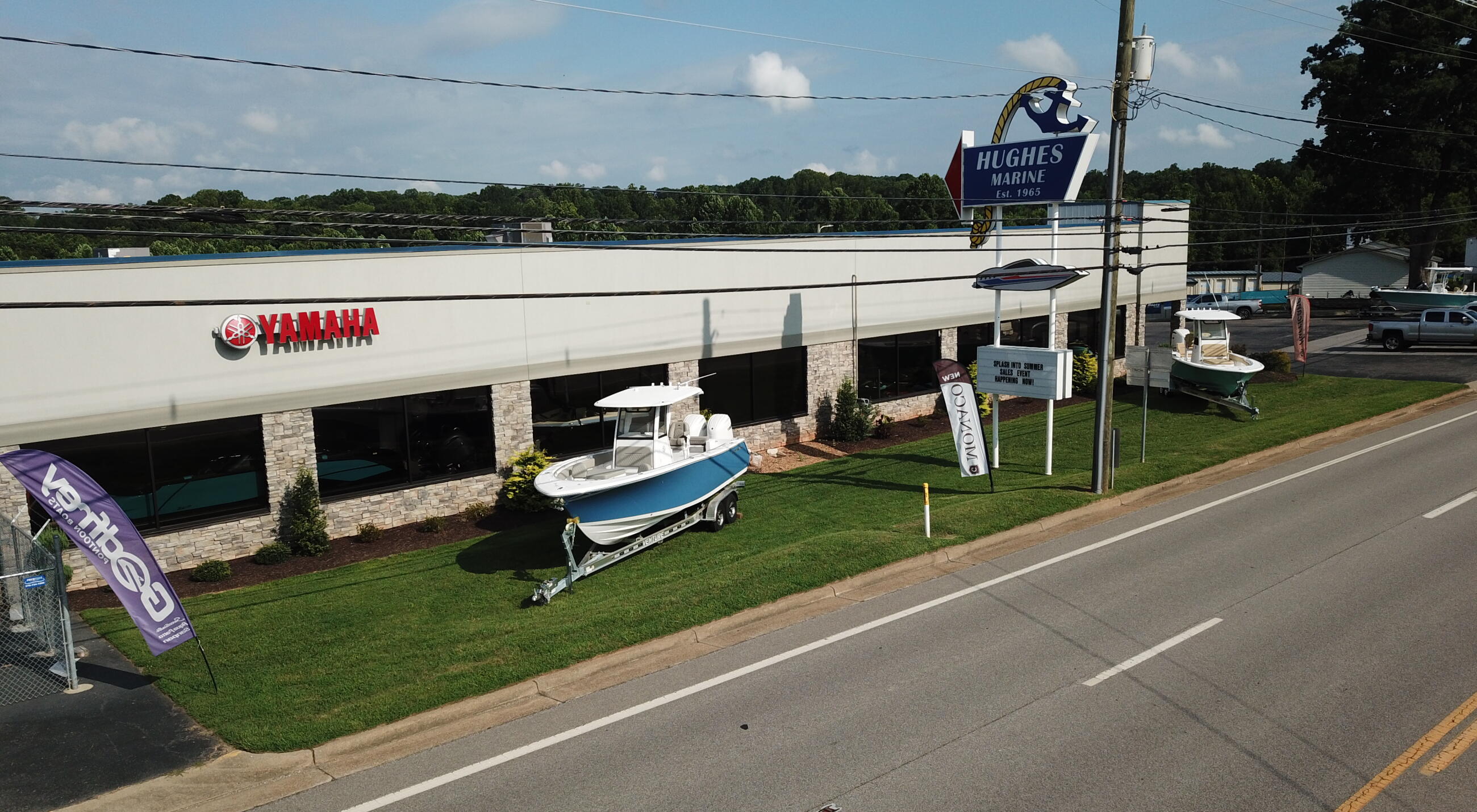 Hughes Marine dealership storefront with Yamaha signage and boats displayed on lawn
