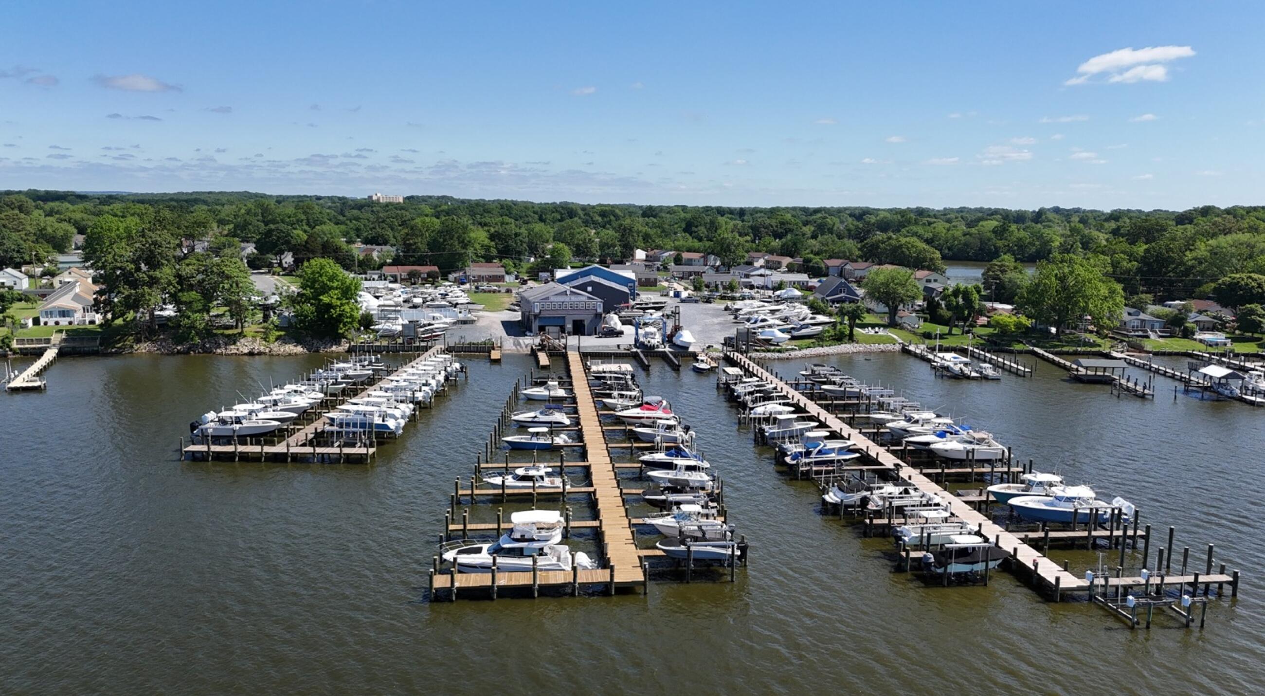 Aerial view of a full-service marina with multiple docked boats, floating docks, and waterfront buildings surrounded by residential areas