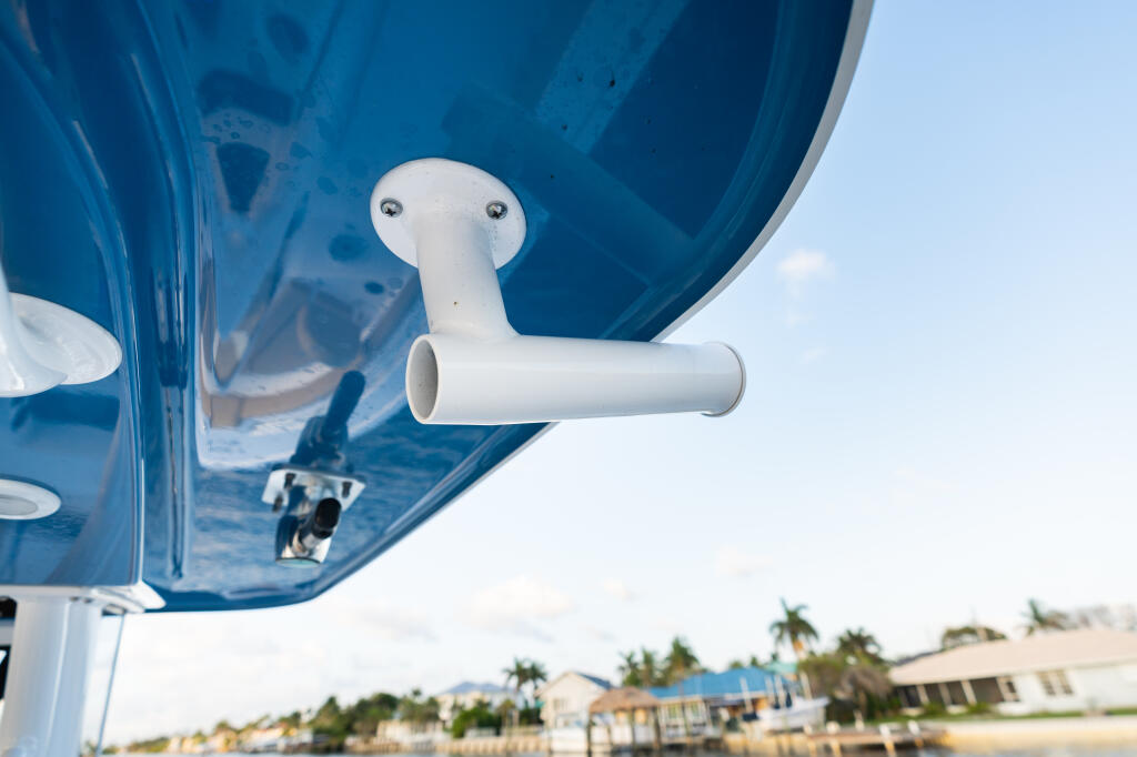 White ventilation outlet mounted on the underside of a blue hard-top canopy with marina buildings visible below