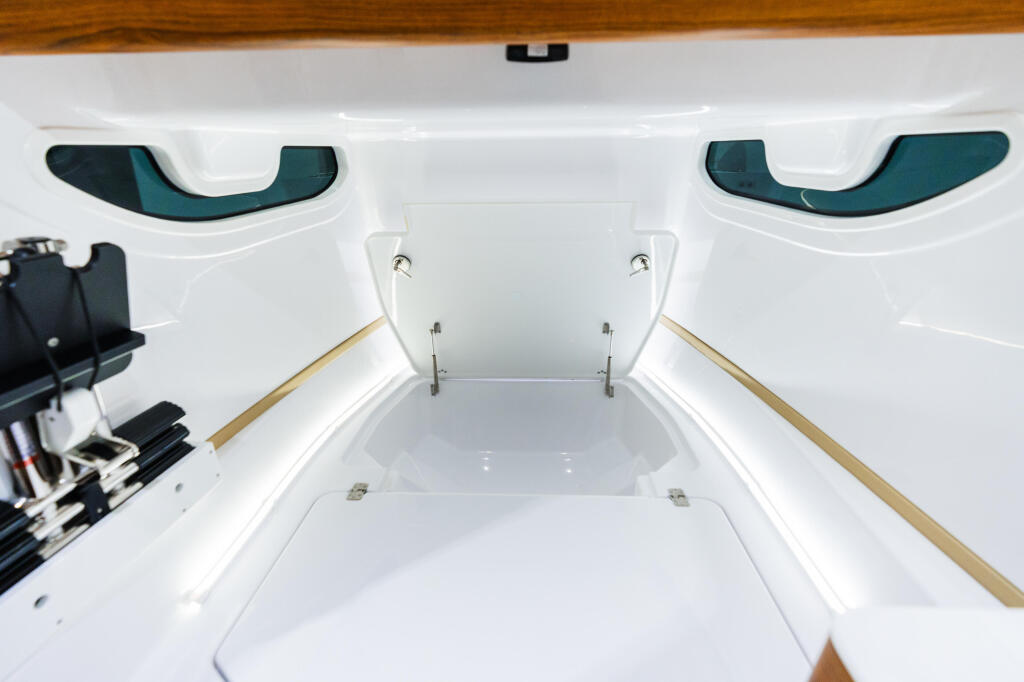 Interior cabin view of boat with two teal-trimmed windows, wooden trim rails, and white fiberglass walls