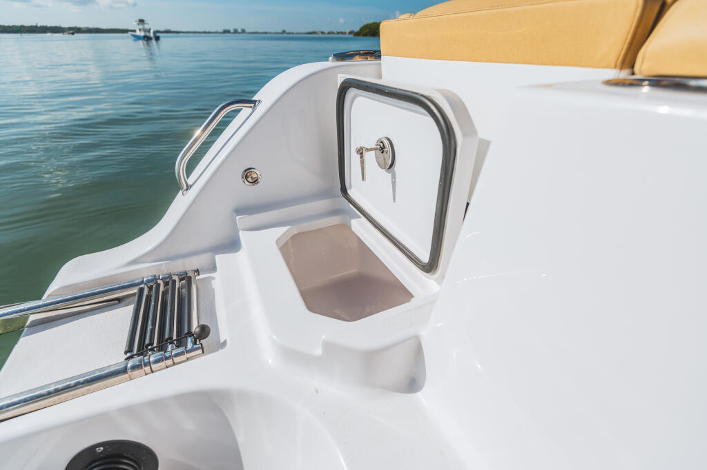 Center console boat cabin door and storage compartment with tan canopy and calm water backdrop