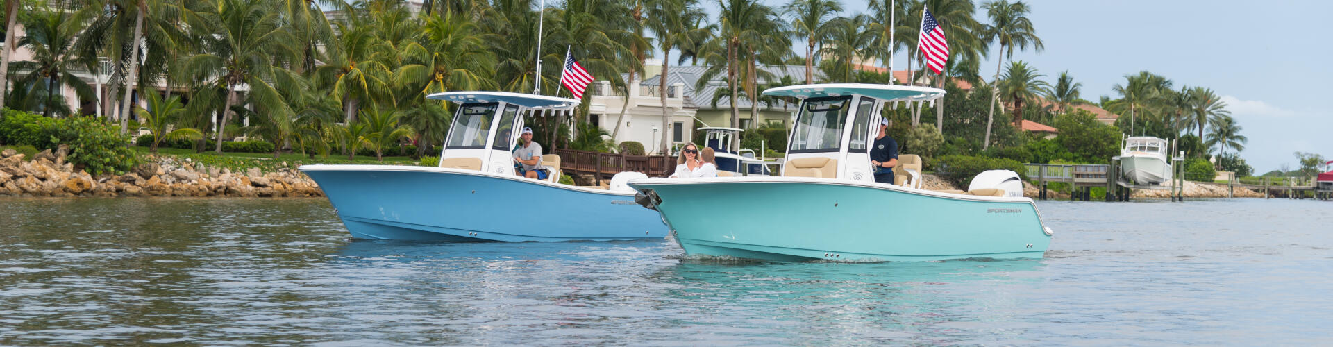 Two blue and turquoise center console boats anchored in shallow tropical waters near palm-lined shore