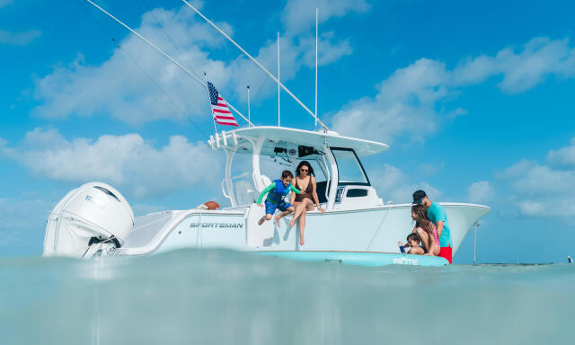 Family with children enjoying shallow turquoise waters from a white sportsman boat anchored at a sandbar